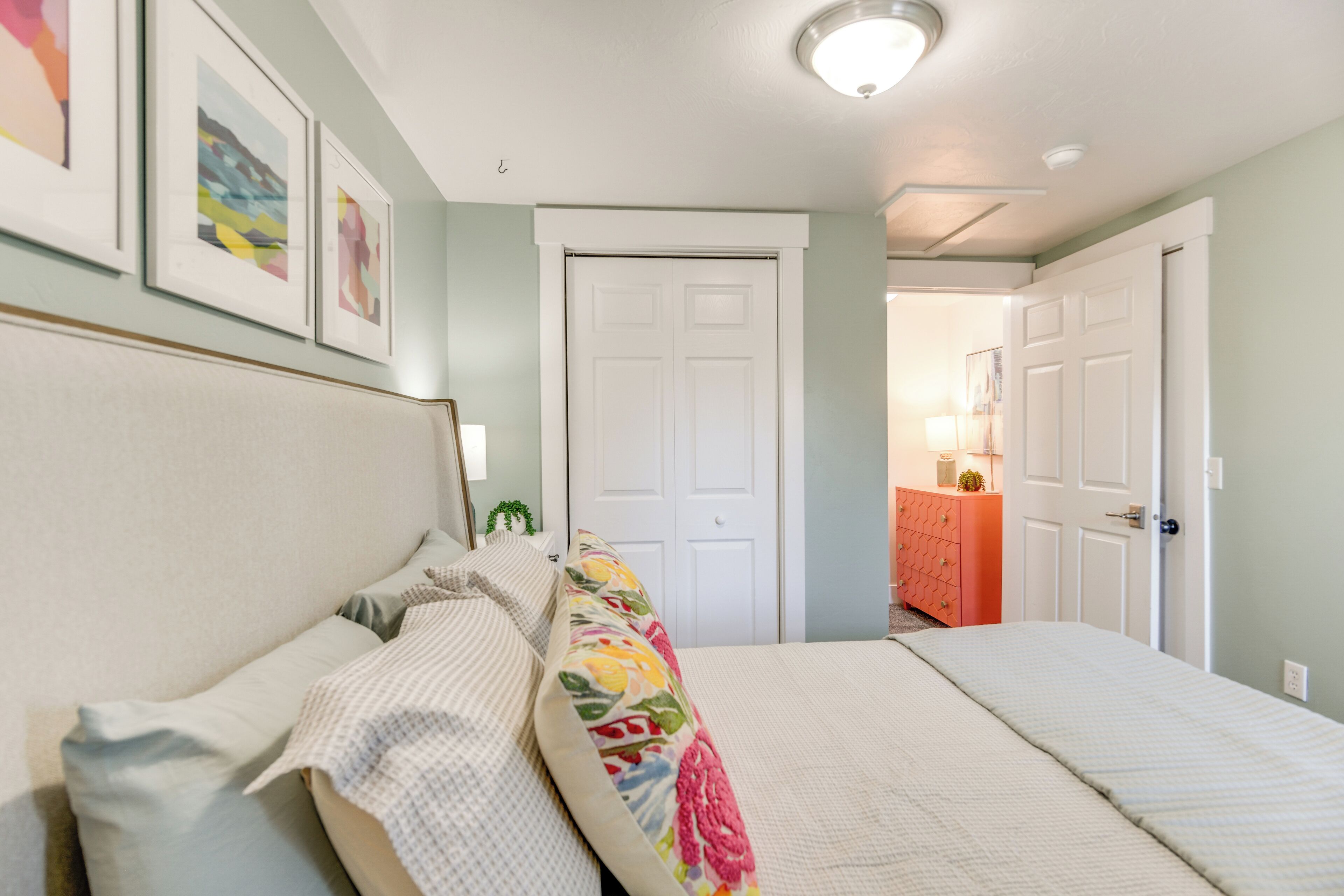 A bedroom with a bed, a dresser, and a door.