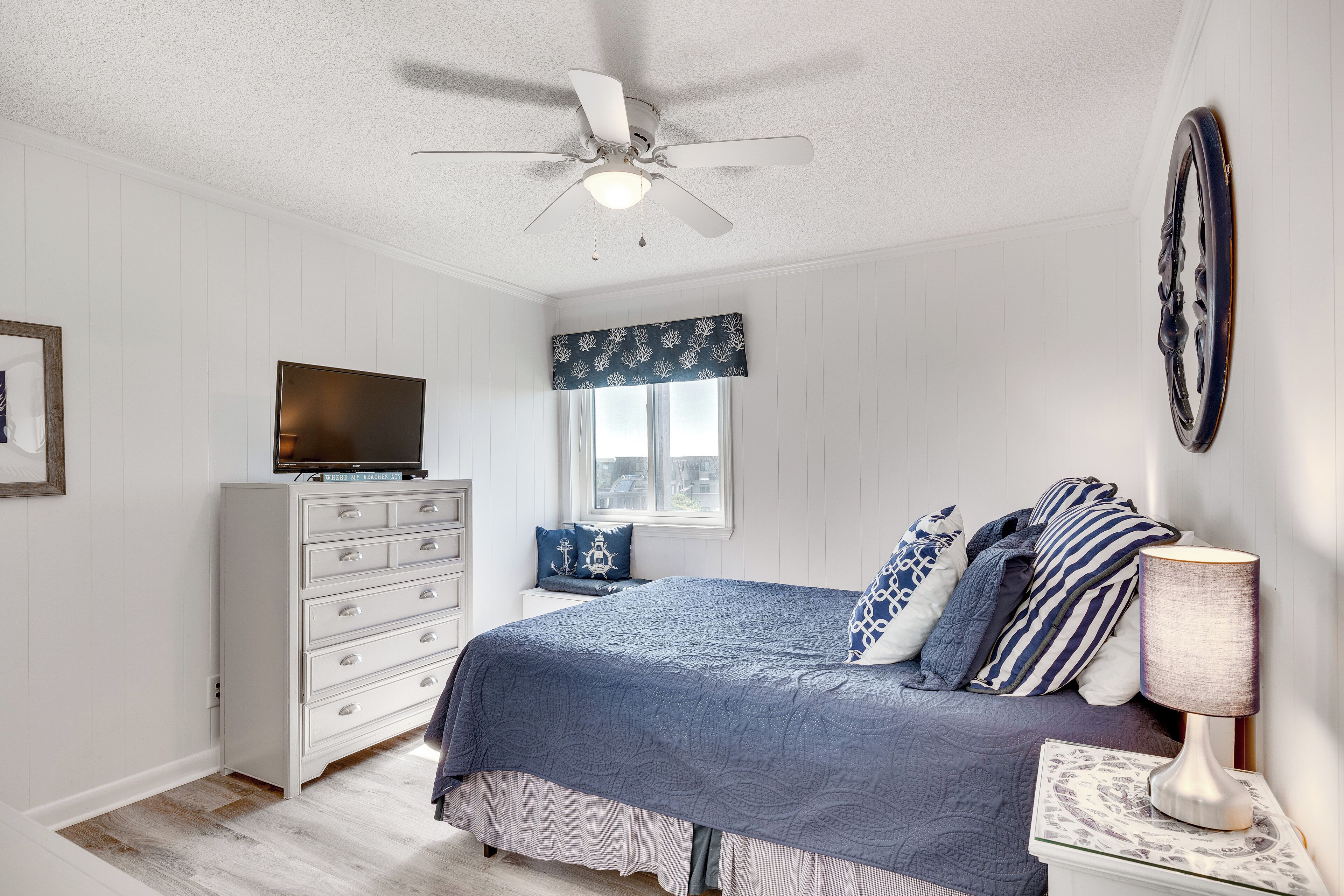 Ein Schlafzimmer mit Bett, Schminktisch, Fernseher und Deckenventilator.