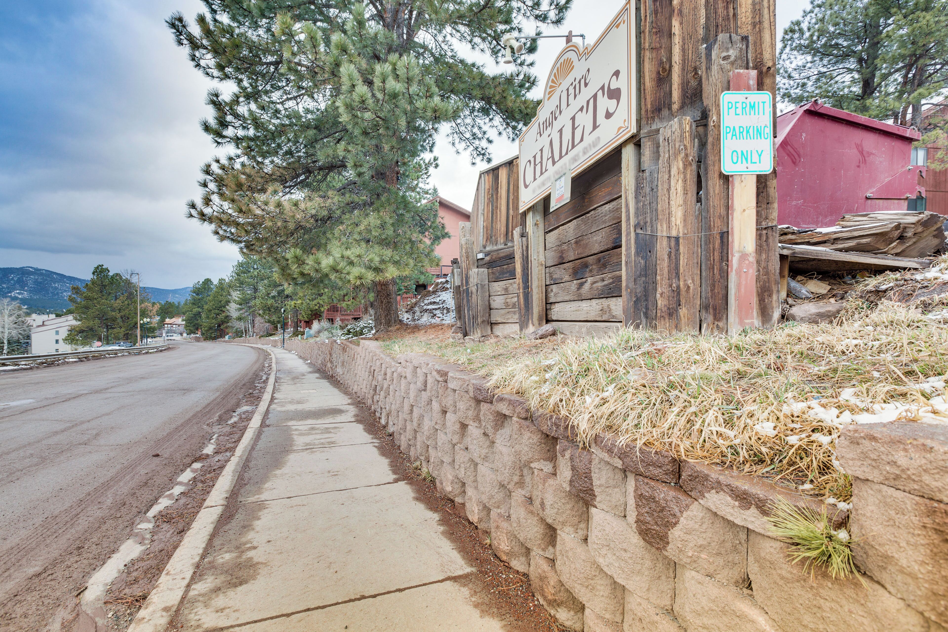 A street with a wooden sign for 'Angel Fire Chalets' and a 'Permit Parking Only' sign.