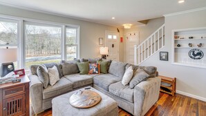 A modern living room with a sectional sofa, a coffee table, and a staircase leading to another level. - Saugerties Farmhouse: Sauna & Countryside Views (Saugerties)