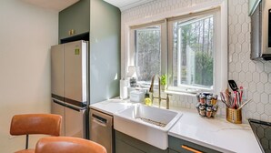 A modern kitchen with a built-in dishwasher, a stainless steel refrigerator, a double sink, and a window with a view of trees. - Saugerties Farmhouse: Sauna & Countryside Views (Saugerties)