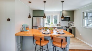 A modern kitchen with a central island, bar stools, pendant lighting, and a large window providing natural light. - Saugerties Farmhouse: Sauna & Countryside Views (Saugerties)