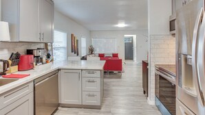 Eine moderne Küche mit einer zentralen Kochinsel, integrierten Geräten und einem roten Sofa im Essbereich.