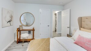 Un dormitorio con una cama, una consola de madera, un espejo y una puerta.