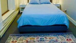 A bedroom with a bed, two bedside tables, a nightstand, a patterned rug, and a ceiling light. - Modern style in historic building in downtown Bath (Bath)