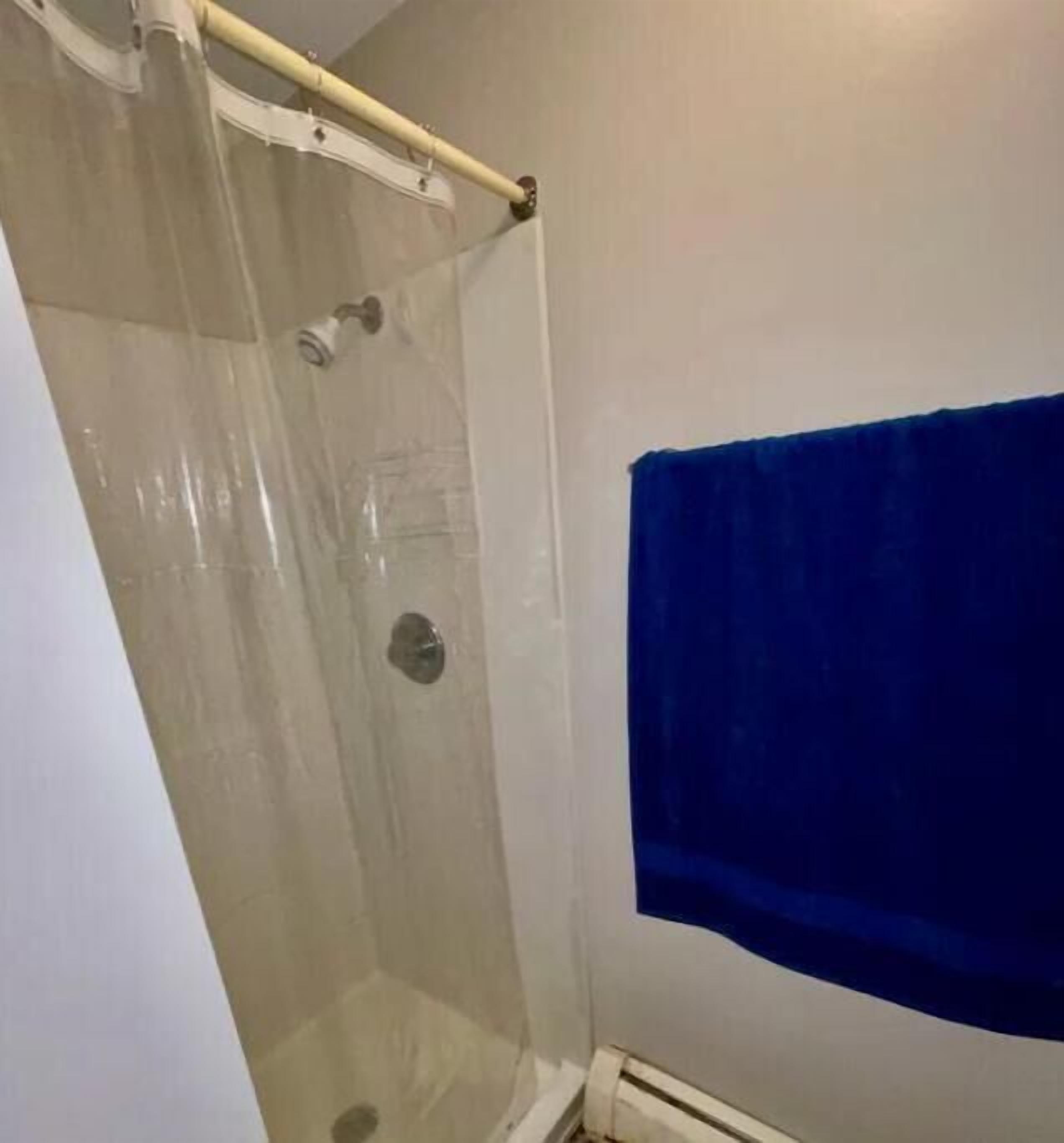 En dusch med en glasdörr, en handdukshängare och en blå handduk som hänger på väggen.