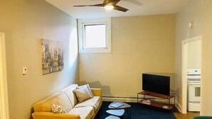 A living room with a sofa, a coffee table, a TV, and a ceiling fan. - Modern style in historic building in downtown Bath (Bath)
