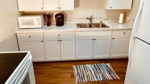 A compact kitchen with white cabinets, a microwave, a coffee maker, and a sink. - Modern style in historic building in downtown Bath (Bath)