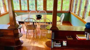 A dining area with a round table, white chairs, and a bookshelf. - Sweet comfy cottage on Small Point Road (Phippsburg)