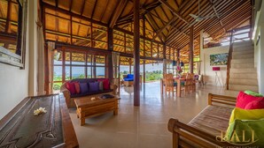 Amplia sala de estar con techo alto, muebles de madera y ventanas grandes que ofrecen vistas al exterior.