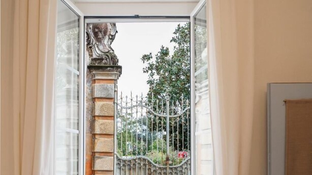 Une salle de bain avec une fenêtre, un radiateur et une porte.