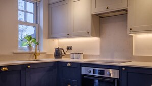 Eine moderne Küche mit dunklen Schränken, einem eingebauten Ofen und einem Fenster mit einer Pflanze.