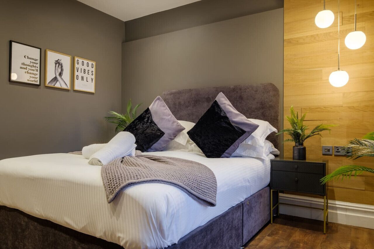 A modern bedroom with a large bed, two side tables, and a wooden accent wall.