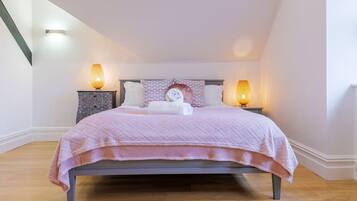 A bedroom with a bed, two bedside tables, and two wall-mounted lamps.