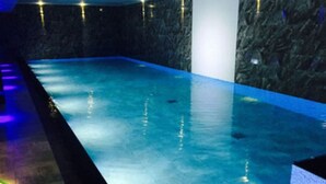 Ein Pool mit einer dunkel, strukturierten Wand und einer Sitzgelegenheit am Beckenrand.