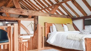 A bedroom with a wooden ceiling, a bed with white bedding, a grey rug, and a wooden chair. - UK46591 - Polecat Barn (Plumpton Green, near Lewes)