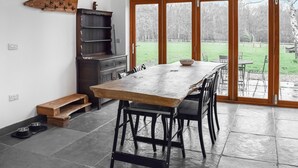 A spacious dining area with a large wooden table and chairs, a built-in bench, and a wooden cabinet. - UK46591 - Polecat Barn (Plumpton Green, near Lewes)