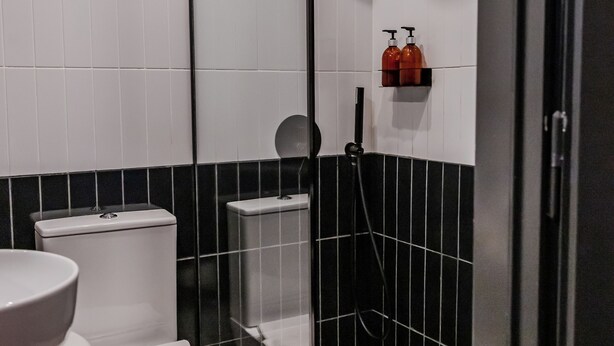 A bathroom with a checkered floor, a glass-enclosed shower, a toilet, and a sink. - Soho Athinas 60 (Athens)