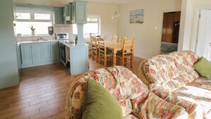 A cozy living room with a patterned sofa and a dining area with wooden chairs and a table. - Sheemore View (Carrick-on-Shannon)