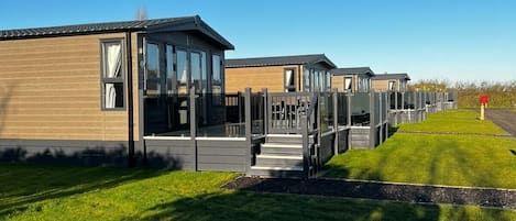 Una hilera de casas móviles modernas con ventanas grandes y un espacio exterior cubierto.