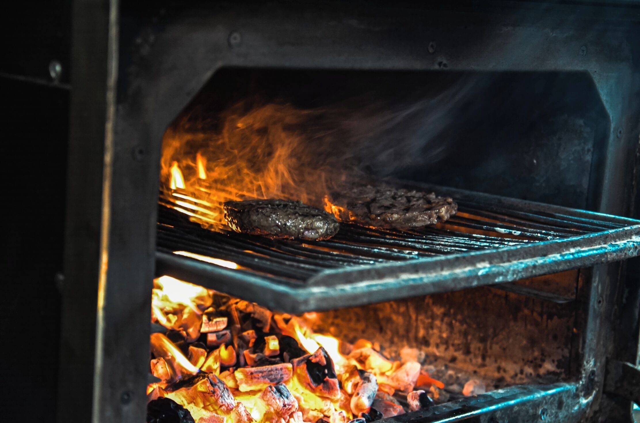 A grill with meat cooking over charcoal.