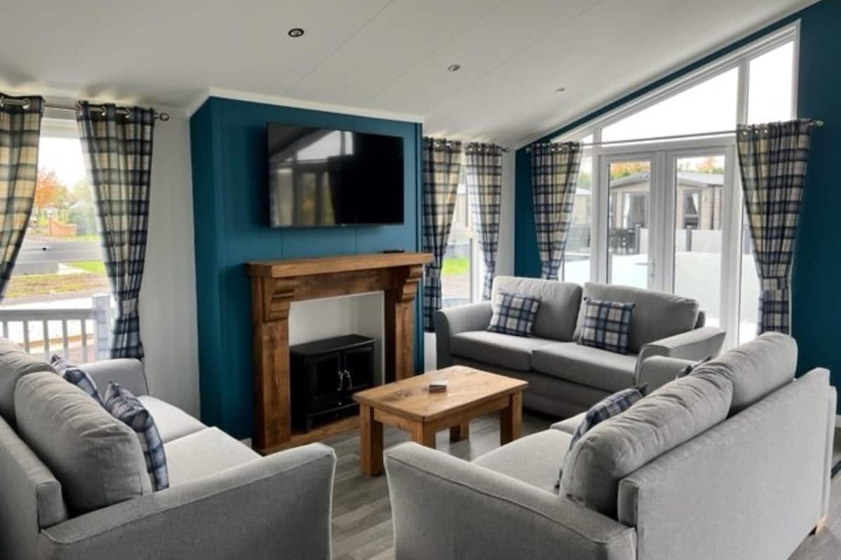 A modern living room with a fireplace, grey sofas, and a television.