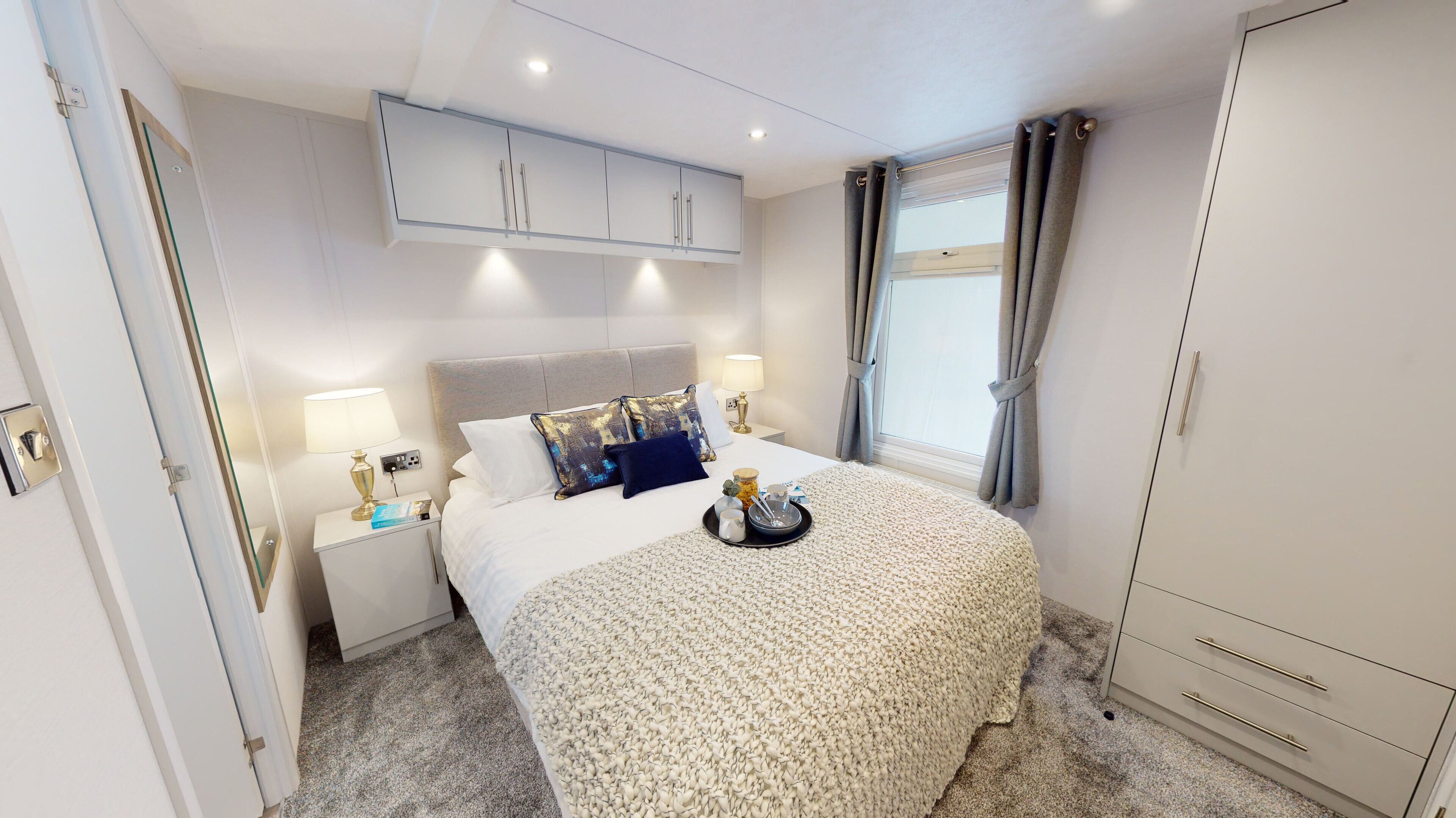 A hotel room with a bed, nightstands, a wardrobe, and a window with curtains.