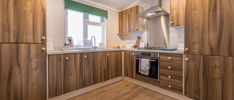 A kitchen with wooden cabinets, a stainless steel range hood, and a window with a green blind.
