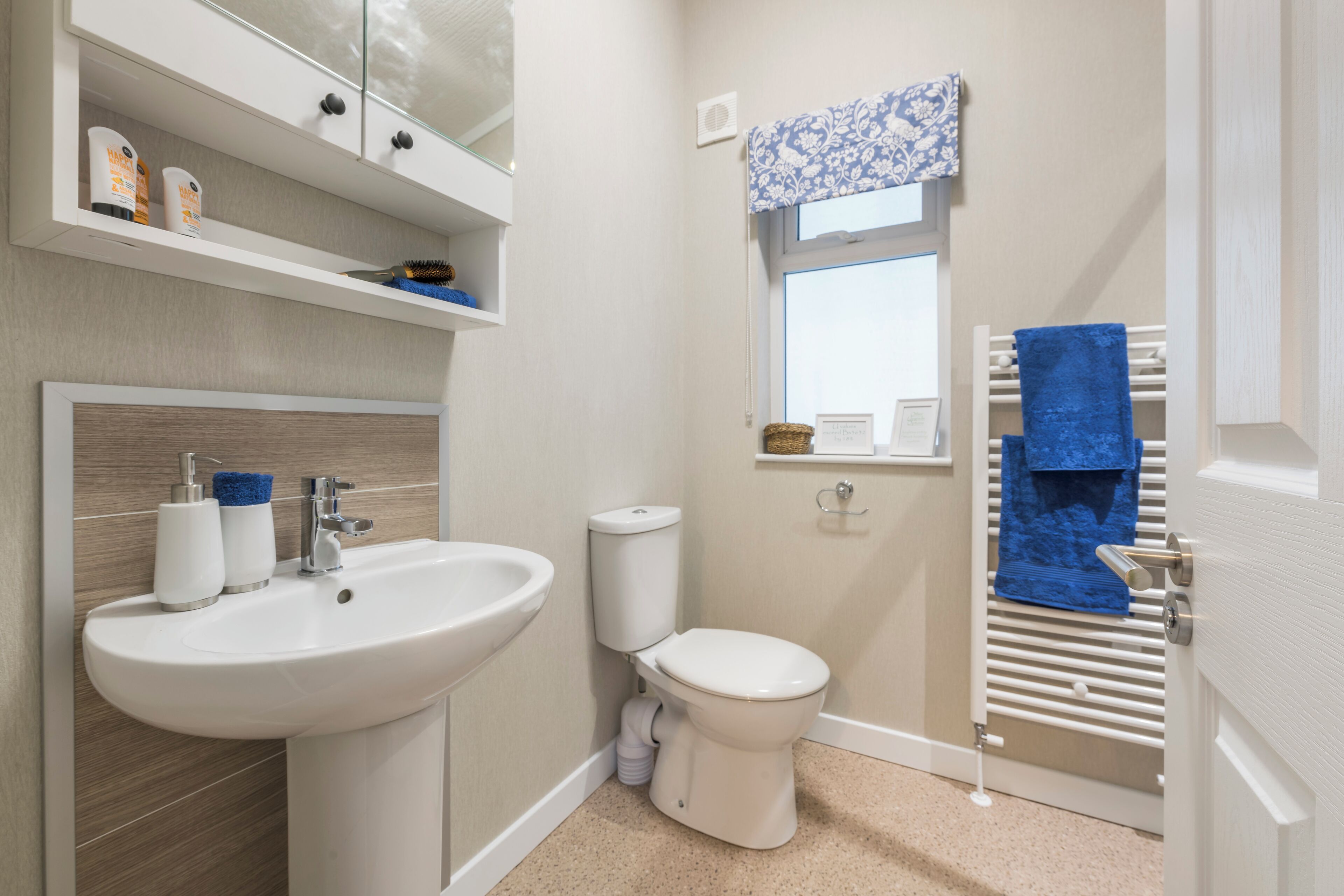 Un baño moderno con lavamanos, inodoro y toallero blancos.