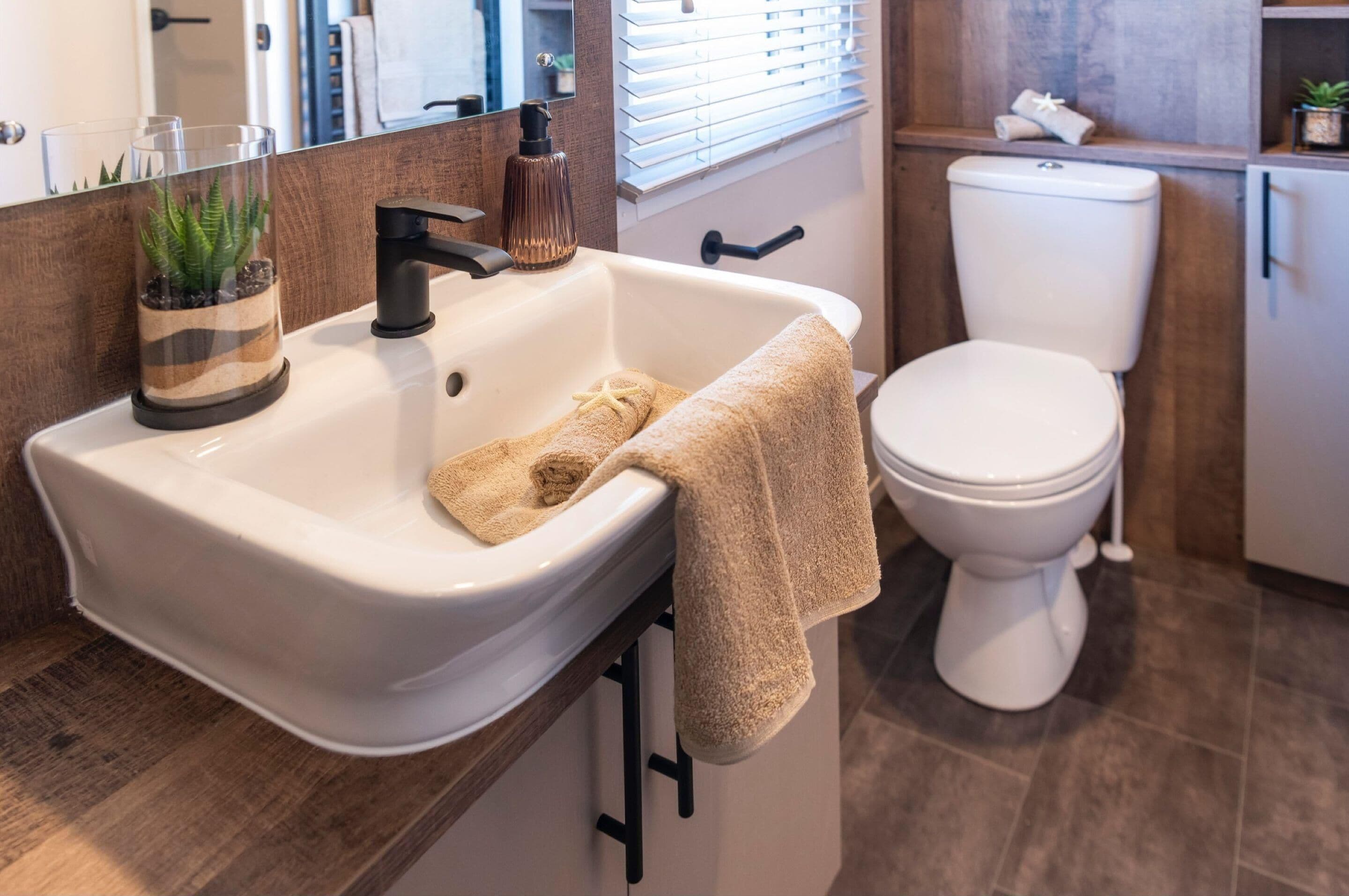 A bathroom with a white sink, a towel, a toilet, and a mirror.