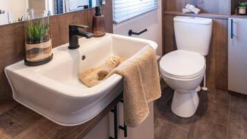 A bathroom with a white sink, a towel, a toilet, and a mirror.