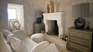 Une pièce avec un canapé blanc, une cheminée, une lampe et une commode.