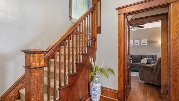 A wooden staircase with a vase of plants at the landing. - Renovated Victorian Home with Private Garden & Fire Pit! (Three Oaks)