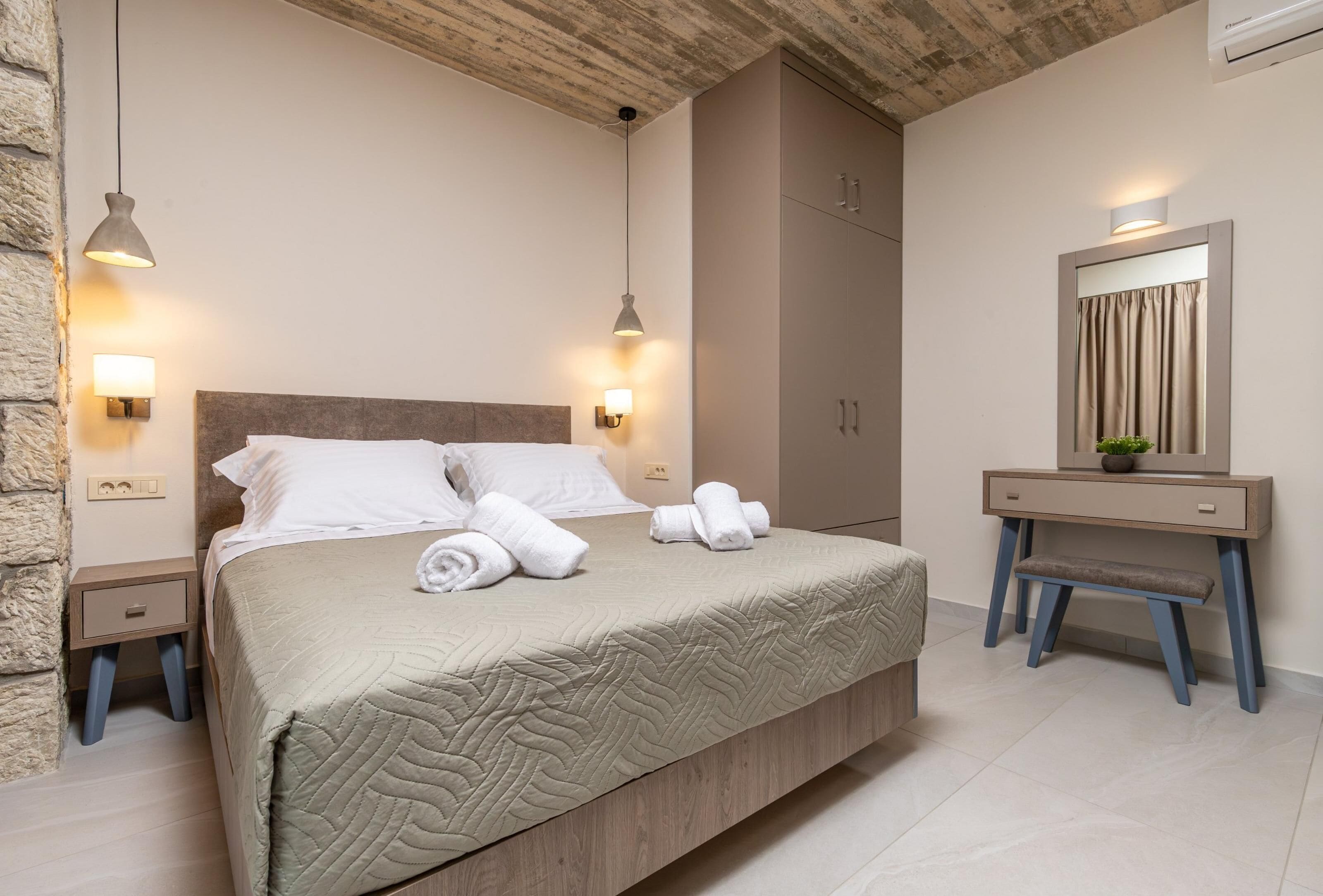 A bedroom with a bed, bedside tables, a desk, and a mirror.