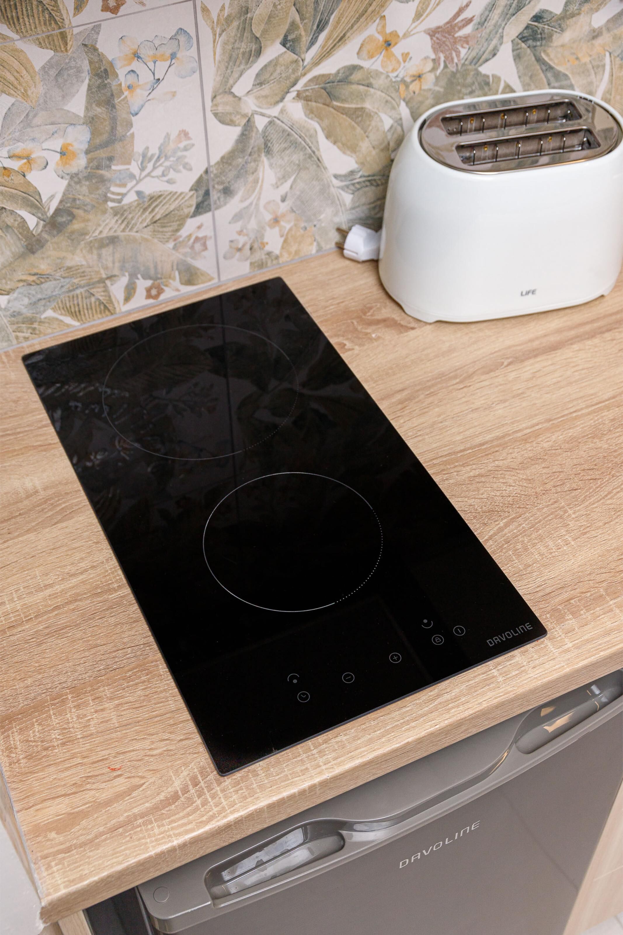 A kitchen with a black induction cooktop, a white toaster, and a dishwasher.
