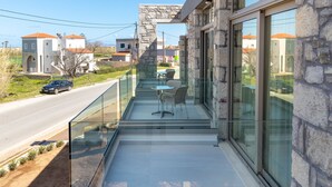 A modern building with a glass balcony overlooking a road. - Achatis Apartments with sea view (Platanias)