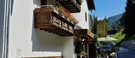 Un hotel llamado 'Buckelhof' con un cartel que indica 'Zipfer' cerca, balcones de madera con jardineras de flores y un camino de entrada de grava.