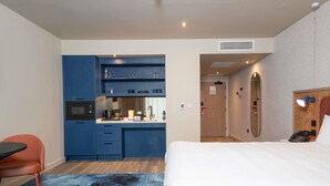 Ein Hotelzimmer mit Bett, Schreibtisch, Stuhl, Küchenzeile und Bad.