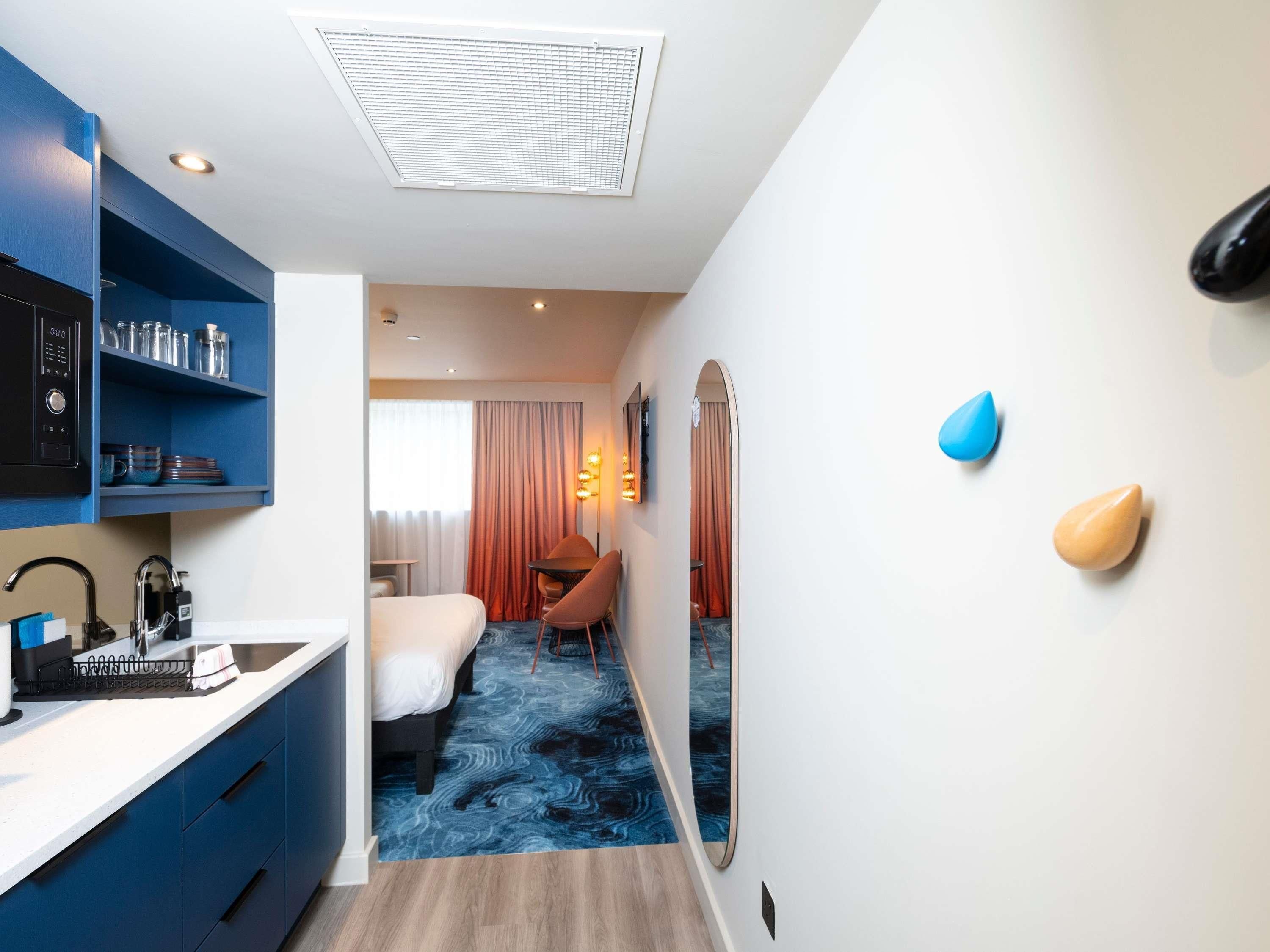 Habitación de hotel con kitchenette, cama, escritorio y baño.