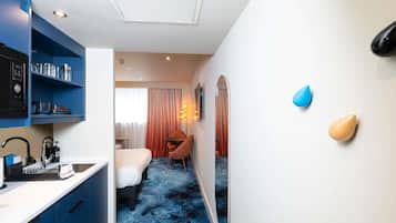 Habitación de hotel con kitchenette, cama, escritorio y baño.