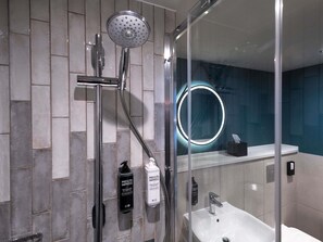 A modern bathroom with a glass-enclosed shower, a white sink, and a mirror with a circular light. - ibis Styles Burton Upon Trent - Hotel & Suites (Burton on Trent)