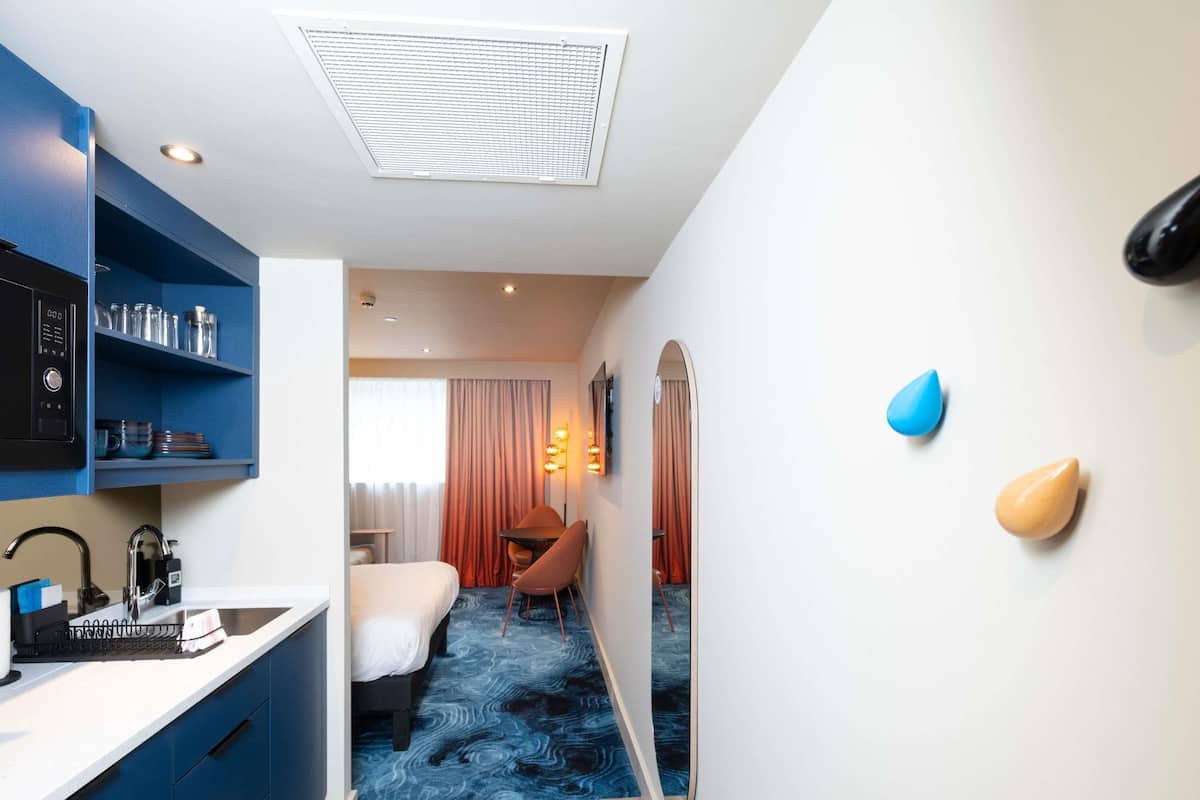 Habitación de hotel con kitchenette, cama, escritorio y baño.