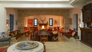 Un salón amplio con chimenea de piedra, techo alto y una gran mesa de comedor.
