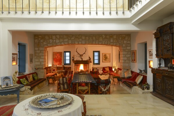 Un salón amplio con chimenea de piedra, techo alto y una gran mesa de comedor.