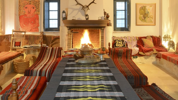 Una sala de estar acogedora con chimenea, alfombras estampadas y una pared de piedra.