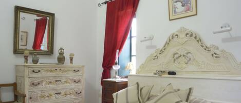A bedroom with a bed, dresser, mirror, and an air conditioning unit.