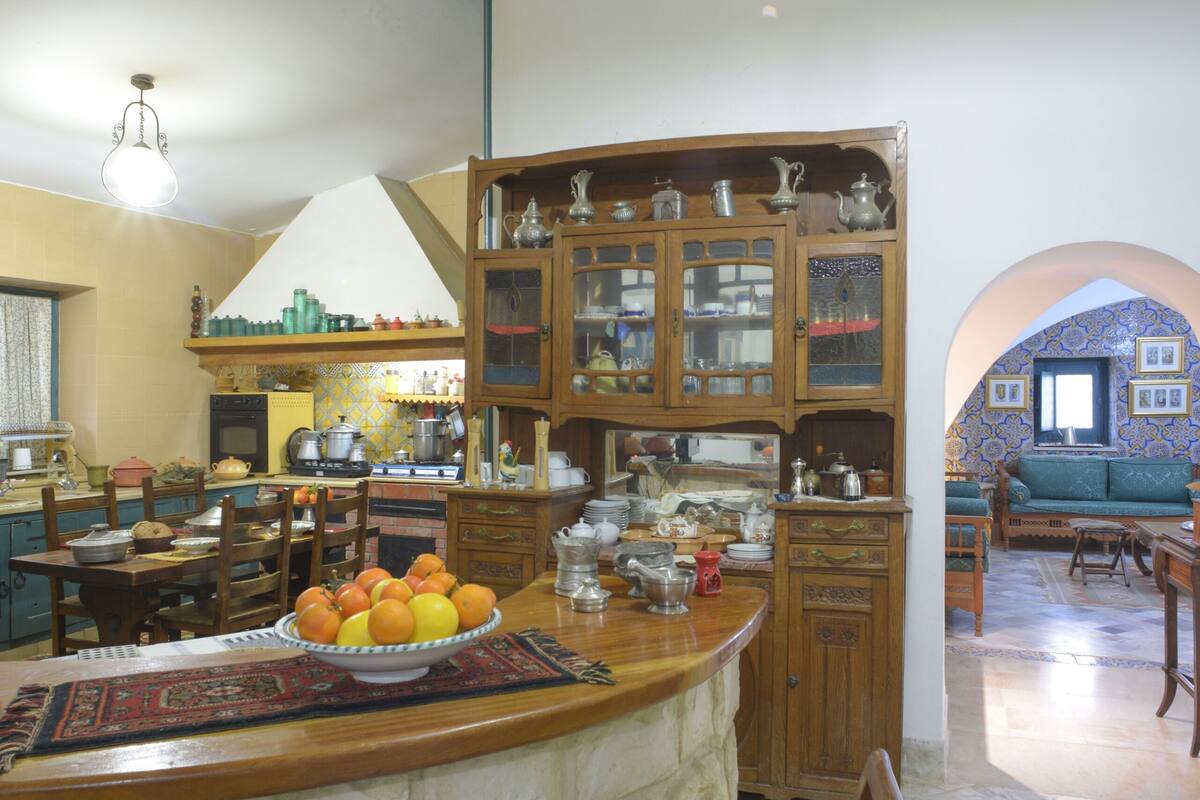 A kitchen with a central island, wooden cabinets, and a dining area with chairs.