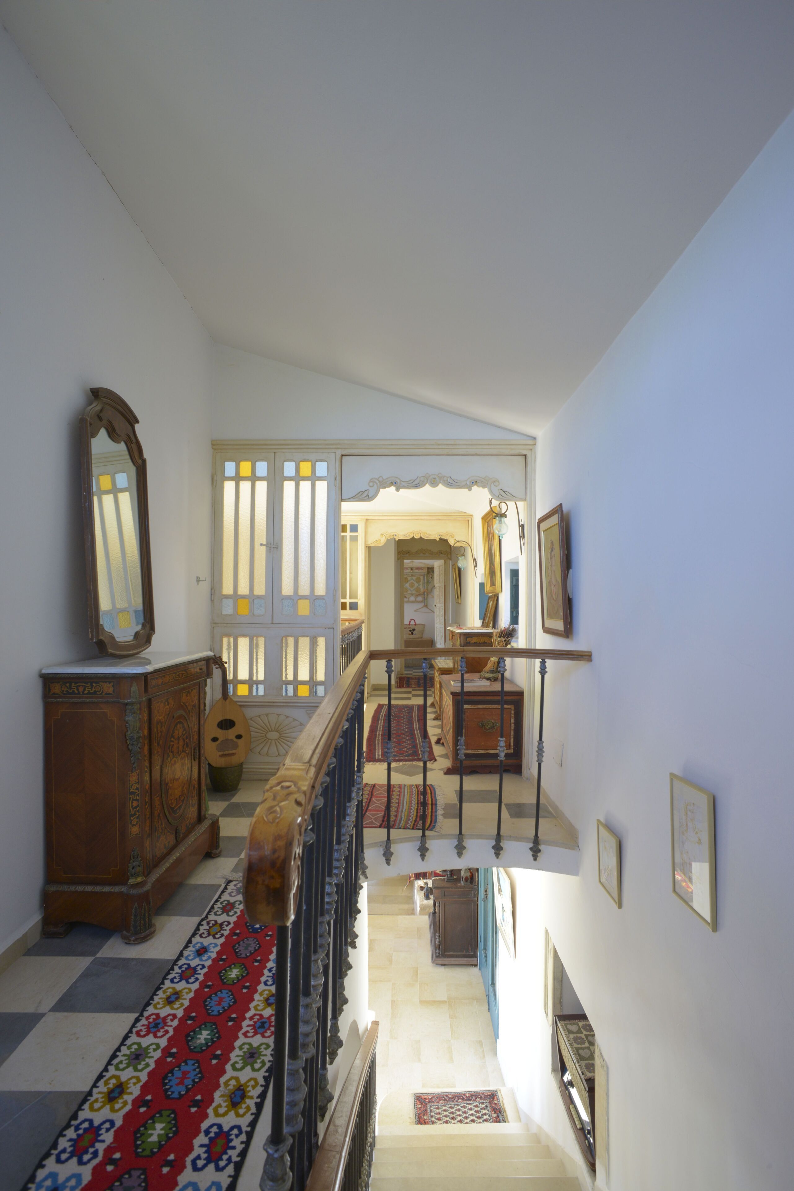 A staircase with a patterned carpet leading to a room with a wooden cabinet and a mirror.