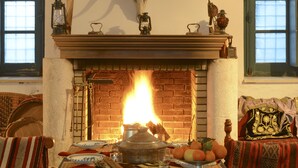Una chimenea con un gran cornamenta montada encima, una mesa dispuesta con comida y un tapete con diseño.