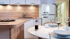 Een moderne keuken met een houten aanrecht, een spoelbak en een witte koelkast. Er staat een eettafel gedekt met borden, glazen en bestek.